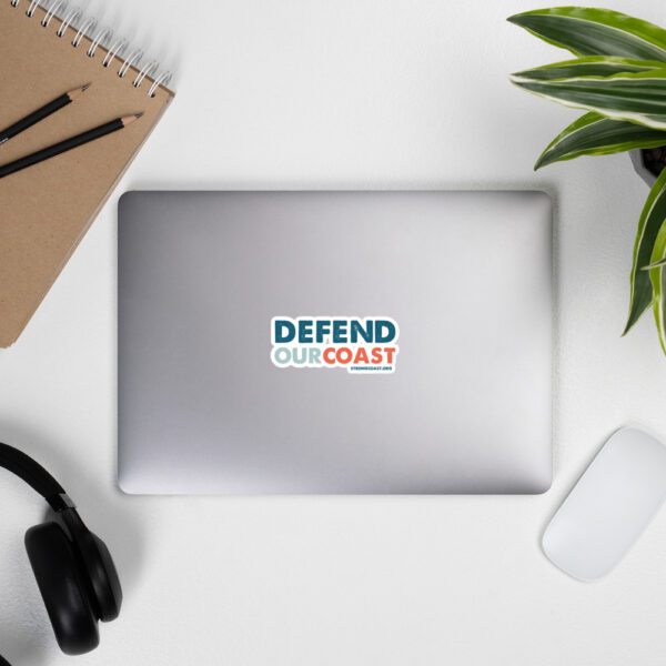 A laptop with a "Defend Our Coast" sticker